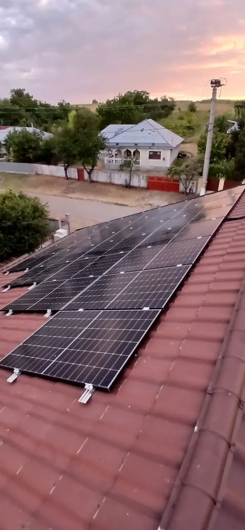 Panouri fotovoltaice montate pe un acoperiș din țiglă roșie, la apus